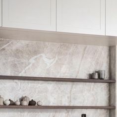 the shelves in the kitchen are made of marble and have vases on each shelf