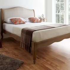 a bed sitting on top of a hard wood floor next to a dresser and window