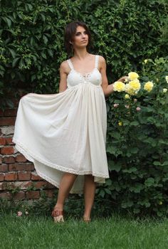 a woman in a white dress standing next to flowers