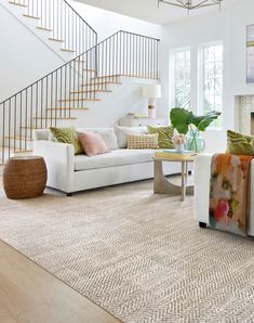 a living room filled with furniture and a fire place in front of a stair case