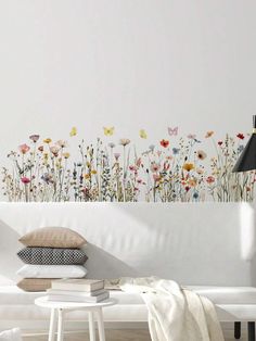 a white couch sitting next to a wall with flowers on it's back side