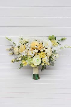 a bouquet of white and yellow flowers against a white painted wood paneled wall,