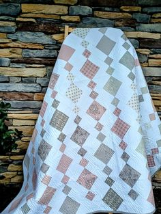 a white and brown quilt sitting on top of a stone wall