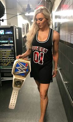 a woman walking down a hallway with a wrestling ring on her hand and a wrestler belt around her waist