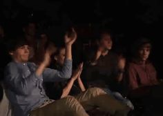 a group of people sitting and standing in front of each other with their hands up