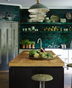 a kitchen with green brick walls and wooden counter tops, surrounded by potted plants