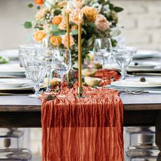 the table is set with silverware and orange napkins