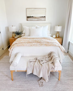 a bed with white linens and pillows in a bedroom next to a painting on the wall