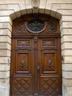 an old wooden door with intricate carvings on the front and side panels, in a stone building