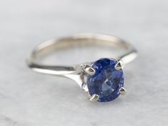 an oval blue sapphire sits on top of a silver ring