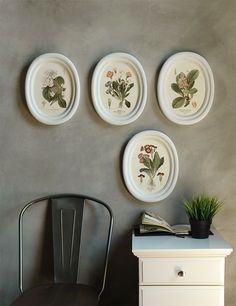 four plates are hanging on the wall above a desk with a chair and potted plant