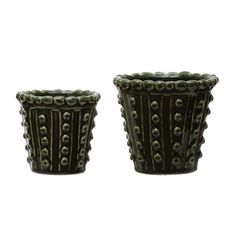 two green vases sitting next to each other on a white surface with black dots