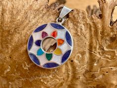 a multicolored glass pendant hangs from a tree branch with wood grain in the background