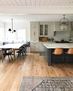 a large kitchen with white cabinets and wood flooring, an island table surrounded by chairs