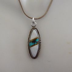 Vintage Native American inlaid pendant, signed. Mark is similar to Hopi artisan, Jesse Josytewa but the piece is inlay rather than overlay so I could be reading it wrong. The mount is sterling silver, unmarked but tests as such, with mother of pearl inlaid with a diagonal stripe of turquoise banded on each side by what I believe to be gold. (I did a vinegar test on it: vinegar will tarnish every metal but gold. No tarnish.) Found without bail; I've added a 16g sterling jump ring. Chain not included. Measures just over 1 3/8" long x 1/2" wide. Total weight 3.11g. All measurements approximate. Estate sale find. Good vintage condition. 👉🏻To continue browsing in the shop please click this link: https://www.etsy.com/shop/SumpnSassyVintage Most of the items I offer are pre-owned and not to be Silver Smithing, Ring Chain, Estate Sale Finds, Diagonal Stripes, Jump Rings, Estate Sale, Mother Of Pearl, Native American, Jewelry Necklace Pendant