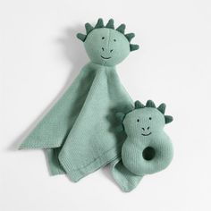 two green knitted toys sitting next to each other on top of a white surface