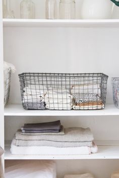 a white shelf filled with folded towels and baskets