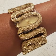 100% Authentic Poshmark Will Authenticate Over $500 Roberto Cavalli Cleopatra Women's Gold Tone Snake Bracelet Watch New With Tags, Includes Box Brushed Gold Tone Oval Analog Face Polished Gold Tone Snake Form Hour And Minute Hands Roberto Cavalli Logo At The 12 O'clock Position Gold Tone Stainless Steel Fixed Bezel Stainless Steel Case Back Polished Gold Tone Raised Texture Stainless Steel Bangle Style Watch Band Push Action Inset Closures Fast Shipping! New To Poshmark? Use Referral Code Mibel High Jewelry Gold, Gold Bangles Black Women, Going Out Jewelry, Roberto Cavalli Jewelry, Gold Wire Wrapped Jewelry, Unique Bracelet Design For Women, West African Jewelry, Gold Snake Bracelet, Gold Earthy Jewelry