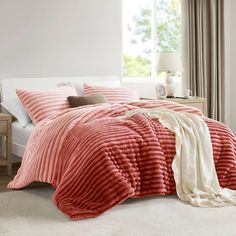 a bed with red and white comforters in a bedroom