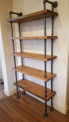 an industrial style shelving unit in a living room with wood floors and white walls