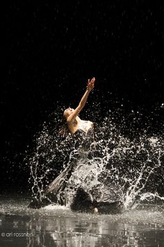 a person jumping into the water on a surfboard in the dark with splashing water