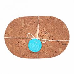 a cork board with a blue tag tied up to it's side on a white background