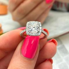 a woman's hand holding a pink manicure with a diamond ring on it