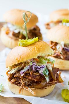 three pulled pork sandwiches with coleslaw and pickles