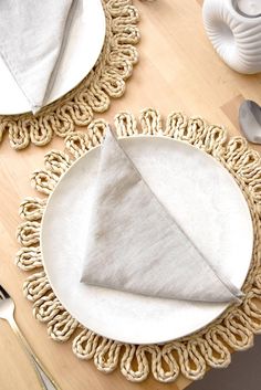 a place setting with napkins and silverware on a wooden tableclothed doily