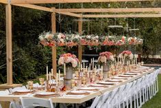 a long table set up with flowers and candles for an outdoor wedding reception in the backyard