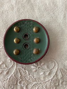 a green button sitting on top of a white table cloth