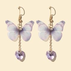 two butterfly shaped earrings hanging from chains with purple crystals on the bottom and gold chain attached to them