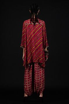 Red short line kurta with multi color stripe prints in sequins georgette, with resham thread mirror embroidered neckline and cowry shells and tassel detailing. Paired with a co-ordinating striped draped dhoti pant.
Component: 2
Embellished, Printed
Neckline: V-Neck
Sleeve Length: Three Quarter
Fabric: Kurta: Georgette; Trousers: Cotton Silk
Color: Red, Multi Color
Asymmetric hem kurta
Cowry shells embellished kurta hem - Aza Fashions Red V-neck Navratri Sets, Navratri Ikat Print Red Sets, Festive Red Ikat Print Sets, Festive V-neck Sets With Bandhani Print, Festive Ikat Print Red Sets, Red Ikat Print Sets For Festivals, Red Ikat Print Festival Sets, Red Block Print Palazzo Set For Eid, Red Block Print Palazzo Set For Diwali