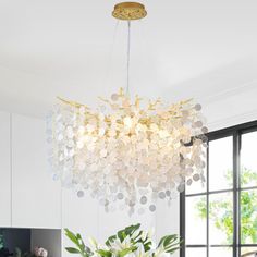 a chandelier hanging over a dining room table with flowers in the vases