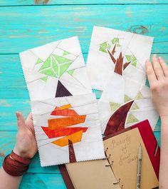 three handmade quilts with trees on them and notebooks next to each other