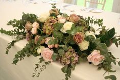 the table is set with flowers and greenery for an elegant centerpiece on it