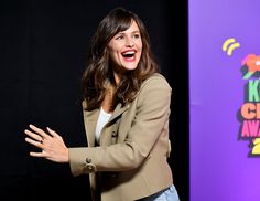 a woman standing in front of a purple wall with her hands out to the side