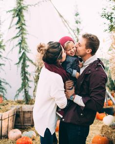 a man, woman and child standing in front of pumpkins