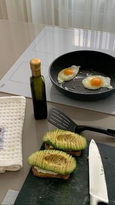 two slices of avocado sitting on top of a cutting board next to a knife