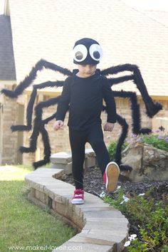 a little boy in a spider costume running down the sidewalk