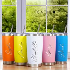 four different colored tumblers with straws in front of a window and the words give me on them