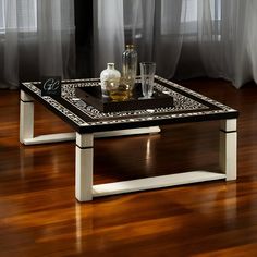 a black and white coffee table sitting on top of a hard wood floor next to a window