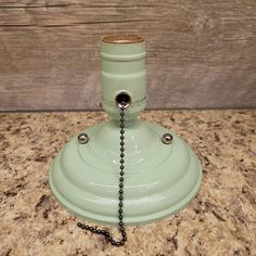 an old fashioned green lamp with a chain hanging from it's end on a counter