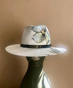 A white Toyo straw is hand-painted with water color and blocked into a fedora shape. Trimmed with western hat band . Head size is adjustable White Toquilla Straw Western Fedora, White Western Fedora In Toquilla Straw, White Toquilla Straw Hat Bands For Vacation, White Western Toquilla Straw Hat, White Toquilla Straw Fedora With Short Brim, White Country Hat In Toquilla Straw, White Toquilla Straw Summer Hat, White Short Brim Fedora In Toquilla Straw, White Country Style Hat In Toquilla Straw