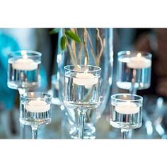 candles are lit in wine glasses on a table