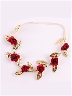 a gold and red necklace with roses on it's side, sitting on a white surface