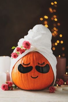 a pumpkin with a towel wrapped around it's head sitting on a table next to candles