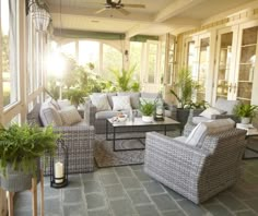 a living room filled with lots of furniture next to a window covered in plants and potted plants