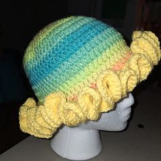 a crocheted hat with yellow flowers on top of a white mannequin head