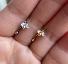 two small diamond studs in the palm of someone's hand, one is gold and the other is white